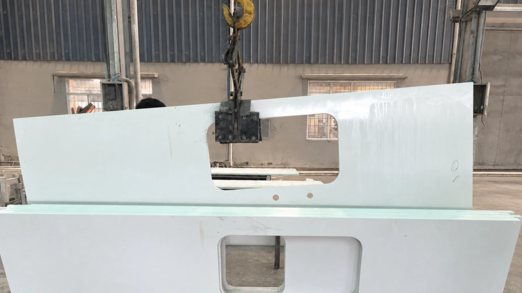 Prefabricated quartz countertop with sink cutout being lifted during factory fabrication